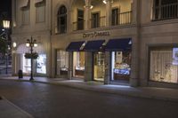 a store is displayed on the sidewalk of this town street at night in a city