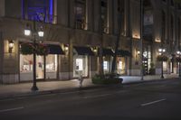 the shops of an upscale business are empty on a street corner at night with colorful lights