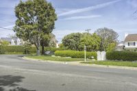 a street with a road markers, trees and bushes along side a residential house entrance