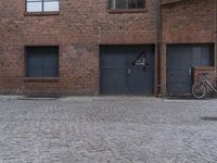 a bicycle leaning against a red brick wall and a door and window on a brick building