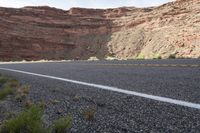 a person riding a motorcycle along a narrow road through rocks and sand cliffs a grassy area on both sides