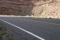 a person riding a motorcycle along a narrow road through rocks and sand cliffs a grassy area on both sides