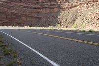 a person riding a motorcycle along a narrow road through rocks and sand cliffs a grassy area on both sides