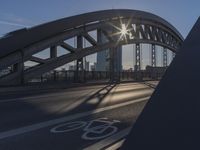 a bicycle path on a bridge over the street in the city sunbeams on the railing