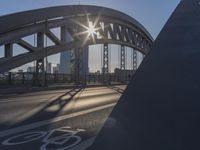 a bicycle path on a bridge over the street in the city sunbeams on the railing