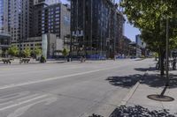 a man riding a bike down a street next to tall buildings and trees with a bunch of animals on the sidewalk