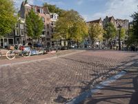 several bikes are parked on an empty cobblestone street near buildings and a gate