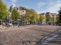 several bikes are parked on an empty cobblestone street near buildings and a gate