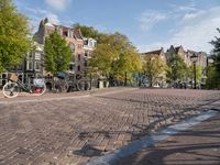 several bikes are parked on an empty cobblestone street near buildings and a gate