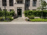 bicycles are parked outside of a beige building with white trims and brickwork on the entrance