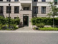 bicycles are parked outside of a beige building with white trims and brickwork on the entrance