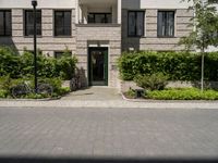 bicycles are parked outside of a beige building with white trims and brickwork on the entrance