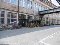 a group of bikes are parked against the wall of a building with a bridge above it