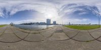 an empty field and a body of water in a big city, taken through some very distorted views