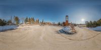 a big dirt pile next to the highway near the forest and large building with tall trees