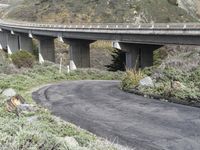 an open country road with a bridge spanning it's width with a car on top