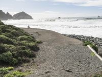 a man is riding his surfboard in the water at beach, waves, rocks, and large rock shoreline