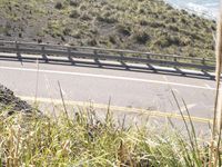 a person riding a skateboard down a road near the ocean in the daytime,