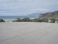 an empty parking lot that leads down to the beach and ocean along with rocks in front