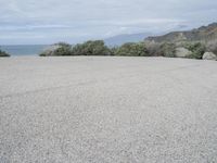 an empty parking lot that leads down to the beach and ocean along with rocks in front