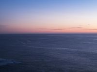 large body of water with some hills on the top and sea below, at sunset