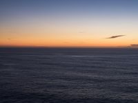 large body of water with some hills on the top and sea below, at sunset