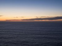 large body of water with some hills on the top and sea below, at sunset