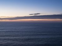 large body of water with some hills on the top and sea below, at sunset