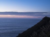 large body of water with some hills on the top and sea below, at sunset