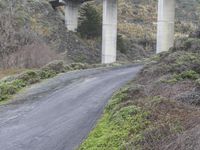 a street in the country side with a train passing under it and overhang a bridge