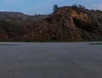 the stop sign is pointing at two separate signs at night time and next to a steep rocky hill