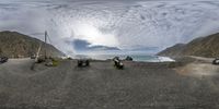 a group of motorcycles parked on a gravel road next to the ocean next to cliffs