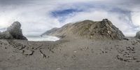 a panoramic photo shows the view of an ocean, rocks and cliffs and sky