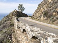 a large stone wall and a curved road by the ocean side in california, usa