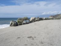 a bunch of rocks by the ocean on a road in front of a cliff with waves