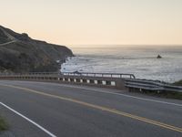 a curve road that is near the beach near the ocean at sunset or sunrise hours