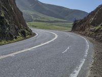 the road has two yellow lines in the middle of it and on the side is an open cliff