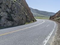 the road has two yellow lines in the middle of it and on the side is an open cliff