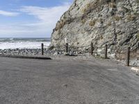 a motorcycle parked in the middle of a gravel road by the ocean with a beach behind it