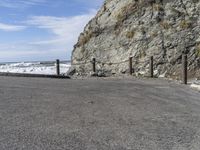 a motorcycle parked in the middle of a gravel road by the ocean with a beach behind it