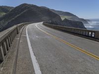 a motorcycle is parked on the side of the road near a ocean shore covered with cliffs