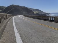 a motorcycle is parked on the side of the road near a ocean shore covered with cliffs