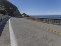 a motorcycle is parked on the side of the road near a ocean shore covered with cliffs