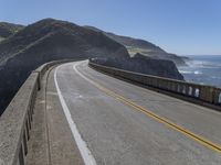 a motorcycle is parked on the side of the road near a ocean shore covered with cliffs