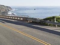 a man on a motorcycle on the road going down the highway near the ocean on a sunny day