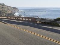 a man on a motorcycle on the road going down the highway near the ocean on a sunny day