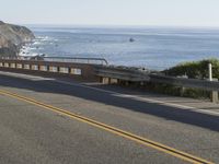 a man on a motorcycle on the road going down the highway near the ocean on a sunny day