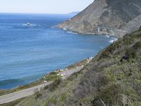 a scenic road on the coast next to the sea and some hills and trees with sea views