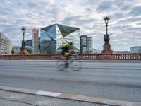 a man riding on the back of a bike across a bridge past other people on bikes