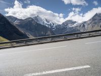 a bike is on a mountain highway with snow covered mountains in the background and the road has no traffic